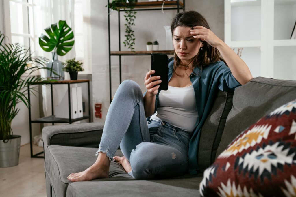 Femme regardant son téléphone l'air incertaine pendant la période d'attente post-ovulatoire