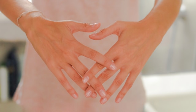 Mains posées devant le ventre d’une femme, évoquant le désir d’enfant et les blocages invisibles de la fertilité.