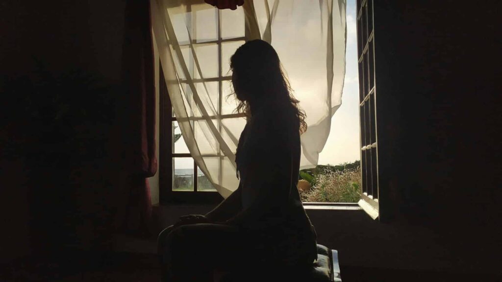 Silhouette de femme assise dans la pénombre illustrant les questions après une FIV négative malgré un contexte favorable