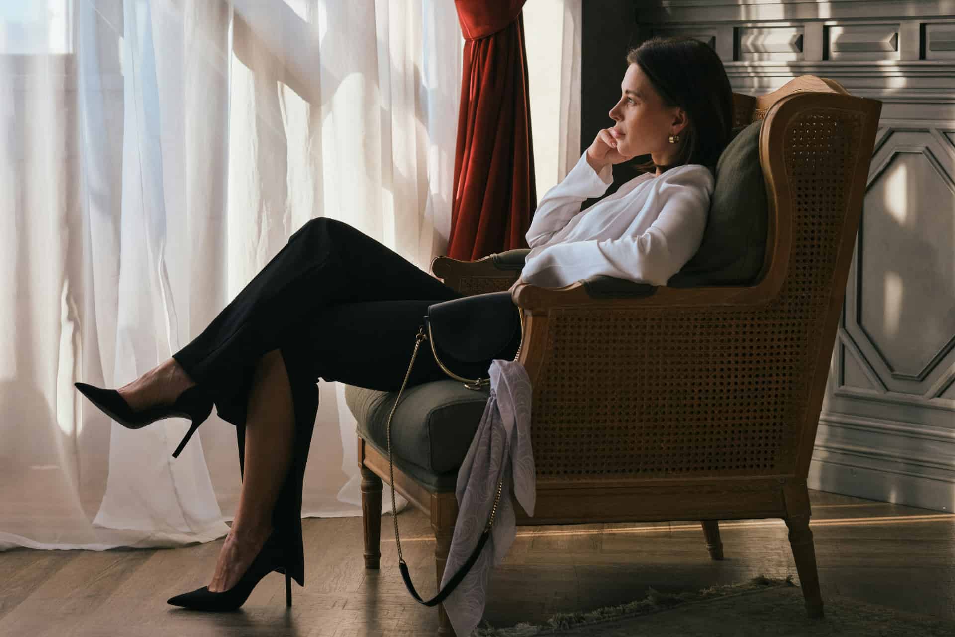 Femme assise près d’une fenêtre après une première FIV échouée, en réflexion sur la suite du parcours