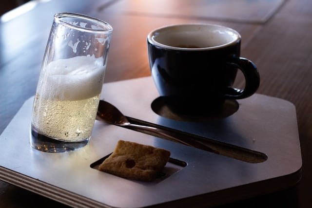 Tasse de café et verre de vin blanc posés sur une table en bois